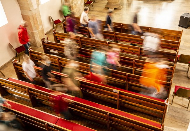 Menschen gehen durch Kirchenbänke