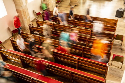 Menschen gehen durch Kirchenbänke
