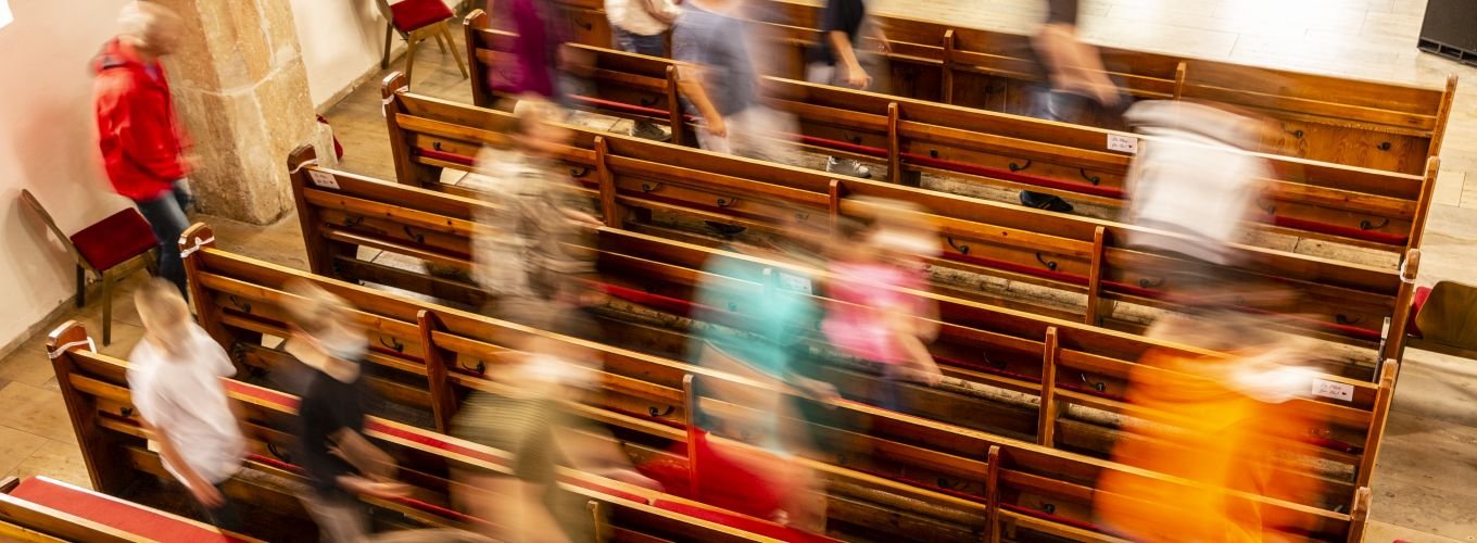 Menschen laufen durch Kirchenbänke